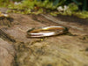 Wound Tiny Gold Stacking Ring hallmark showing sitting on a log