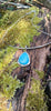 Blue stone pendant with silver tendrils on a silver bar and chain sits on a mossy log