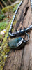 Bud shaped labradorite pendant with a tendril  curling around the string of black lustrous freshwater pearls. With a dreamy elfin it quality sits on a mossy log, the labradorite stone glinting blue and orange in the sunlight.
