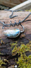 Bud shaped labradorite pendant with a tendril  curling around the oxidised silver spiga chain. With a dreamy elfin it quality sits on a mossy log, the labradorite stone glinting blue and orange in the sunlight.