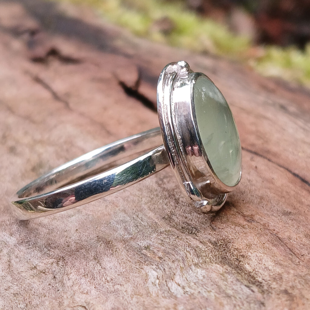 Silver ring with a soft green prehnite stone on a wooden background