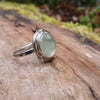 Silver ring with a soft green prehnite stone on a wooden background