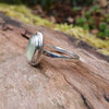 Silver ring with a soft green prehnite stone on a wooden background