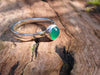 Silver and Green agate stacking ring Sitting on a mossy Woodland log in the sunlight.