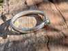 Silver and Peridot stacking ring Sitting on a mossy Woodland log in the sunlight.