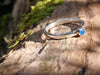 Sterling silver and Blue onyx  stacking ring. Sitting on a mossy log in the sunshine.