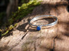 Sterling silver and Blue onyx  stacking ring. Sitting on a mossy log in the sunshine.