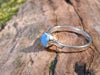 Sterling silver and Opalite stacking ring. Sitting on a mossy log in the sunshine.