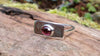 Sterling silver and garnet flat topped ring sitting on a log in the forest.