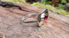Sterling silver and garnet flat topped ring sitting on a log in the forest.