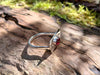 Sterling silver and garnet flat topped ring sitting on a log in the forest.