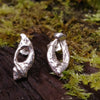 Sterling silver Femscape earrings sitting on a mossy log.