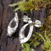Sterling silver Femscape earrings sitting on a mossy log.