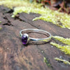 sterling silver stacking ring with  Purple oval amethyst, sitting on a mossy log in the sun