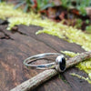 sterling silver stacking ring with Deep bluish Purple oval iolite, sitting on a mossy log in the sun