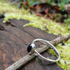sterling silver stacking ring with Deep bluish Purple oval iolite, sitting on a mossy log in the sun.