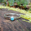 Bright Amazonite stacking ring sitting on a mossy log in the sun