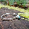 Bright Amazonite stacking ring sitting on a mossy log in the sun