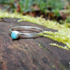 Bright Amazonite stacking ring sitting on a mossy log in the sun