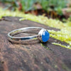 Bright Blue Onyx stacking ring sitting on a mossy log in the sun