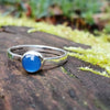 Bright Blue Onyx stacking ring sitting on a mossy log in the sun