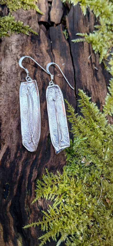 Medium1 melt drop silver earrings on a mossy log