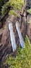 Long melt drop silver earrings on a mossy log in the sunshine.