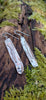 Medium slim melt drop silver earrings on a mossy log