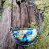 Oxidised silver half moon and chain necklace with tendrils. Sitting on a mossy log.