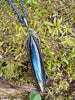 Oxidised silver pendant with a long oval Labradorite stone and a chunky chain sitting on a mossy log.