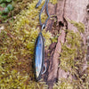 Oxidised silver pendant with a long oval Labradorite stone and a chunky chain sitting on a mossy log.