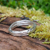 A sterling silver wound strand ring sits on a mossy log 