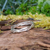A sterling silver wound strand ring sits on a mossy log 
