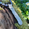 Medium Straight sterling silver melt textured pendant on black freshwater pearl beads. the necklace lies on a mossy woodland log.