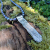 Medium Straight sterling silver melt textured pendant on black freshwater pearl beads. the necklace lies on a mossy woodland log.