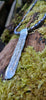 Long Straight sterling silver melt textured pendant on black freshwater pearl beads. the necklace lies on a mossy woodland log.