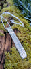 Long Straight sterling silver melt textured pendant on a chunky spiga chain. the necklace lies on a mossy woodland log.