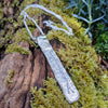 Long Straight sterling silver melt textured pendant on a chunky spiga chain. the necklace lies on a mossy woodland log.