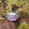 Silver ring with large uncut pale lavender Amethyst sits on a mossy log in the sunshine