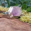 Silver ring with large uncut pale lavender Amethyst sits on a mossy log in the sunshine