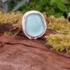 Sterling silver ring with a turquoise oval ish shaped sea glass stone. Sitting on a mossy log in the sunshine.