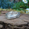 A third molten textured silver ring sits on a mossy log with leaves in the backround. This one has wound and overlapping melted stands.