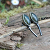 Leaf shaped labradorite stones with silver stems. oxidised silver stud earrings with a dreamy elfin quality sits on a weathered piece of wood, the labradorite stones glinting blue in the sunlight. Shown with the leaves facing upwards and the stems facing in facing down.