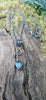 an oxidised silver tendril pendant wraps up and around the oxidised silver spiga chain and down to the bud shaped blue flash labradorite.
on a mossy log.