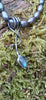 an oxidised silver tendril pendant wraps up and around the black freshwater pearls and down to the bud shaped blue flash labradorite.
sitting on a mossy log in the sunshine.