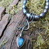 an oxidised silver tendril pendant wraps up and around the black freshwater pearls and down to the bud shaped blue flash labradorite.
sitting on a mossy log in the sunshine.