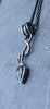 an oxidised silver tendril pendant wraps up and around the oxidised silver spiga chain and down to the bud shaped blue flash labradorite.
on a slate background.