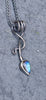 an oxidised silver tendril pendant wraps up and around the oxidised silver spiga chain and down to the bud shaped blue flash labradorite.
on a slate background.
