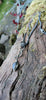 an oxidised silver tendril pendant wraps up and around the oxidised silver spiga chain and down to the bud shaped blue flash labradorite.
on a mossy log.