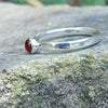 Sterling silver and orange carnelian stacking ring with 4mm round stone. Sitting on a rock